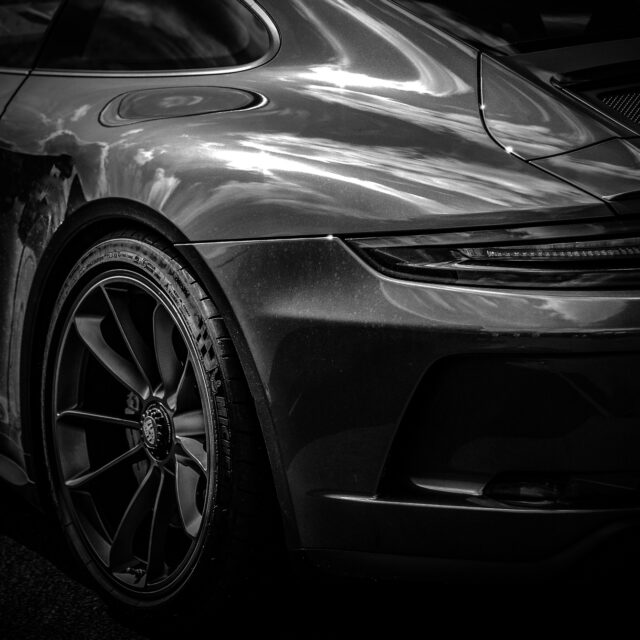 Silver sports car’s rear quarter, showing a dark taillight.
