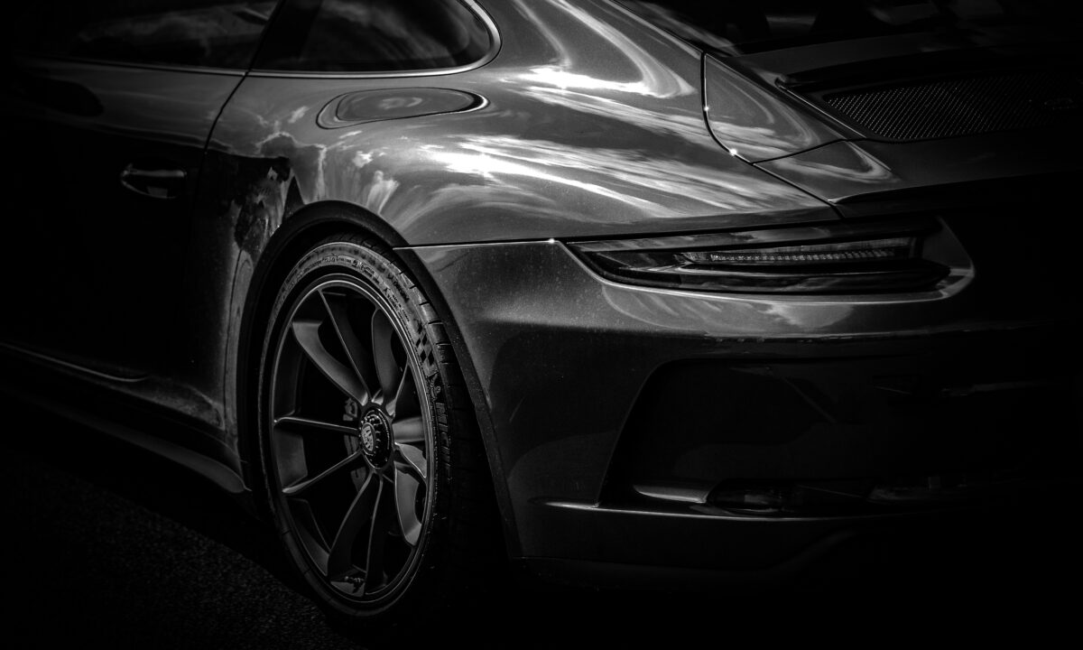 Silver sports car’s rear quarter, showing a dark taillight.